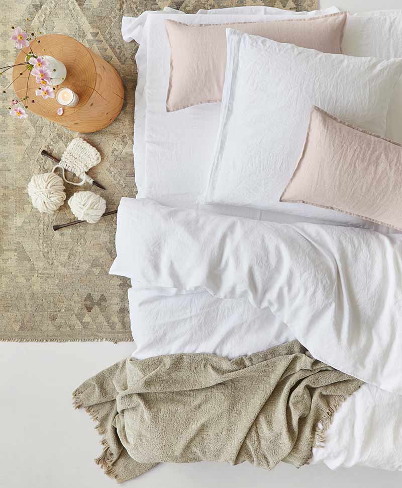 Kissen auf einem Bett mit rosa und weißen Bezügen und einer Bettwäsche