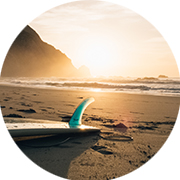 Bild eines am Strand liegenden Surfboardes bei Sonnenuntergang