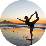 Bild einer Person, die am Strand bei Sonnenuntergang Yoga macht