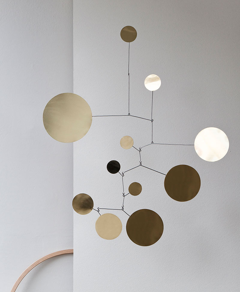 Das handgefertigte Mobile "Circle" hängt an der Decke vor einer grauen Wand in einem minimalistisch eingerichteten Raum