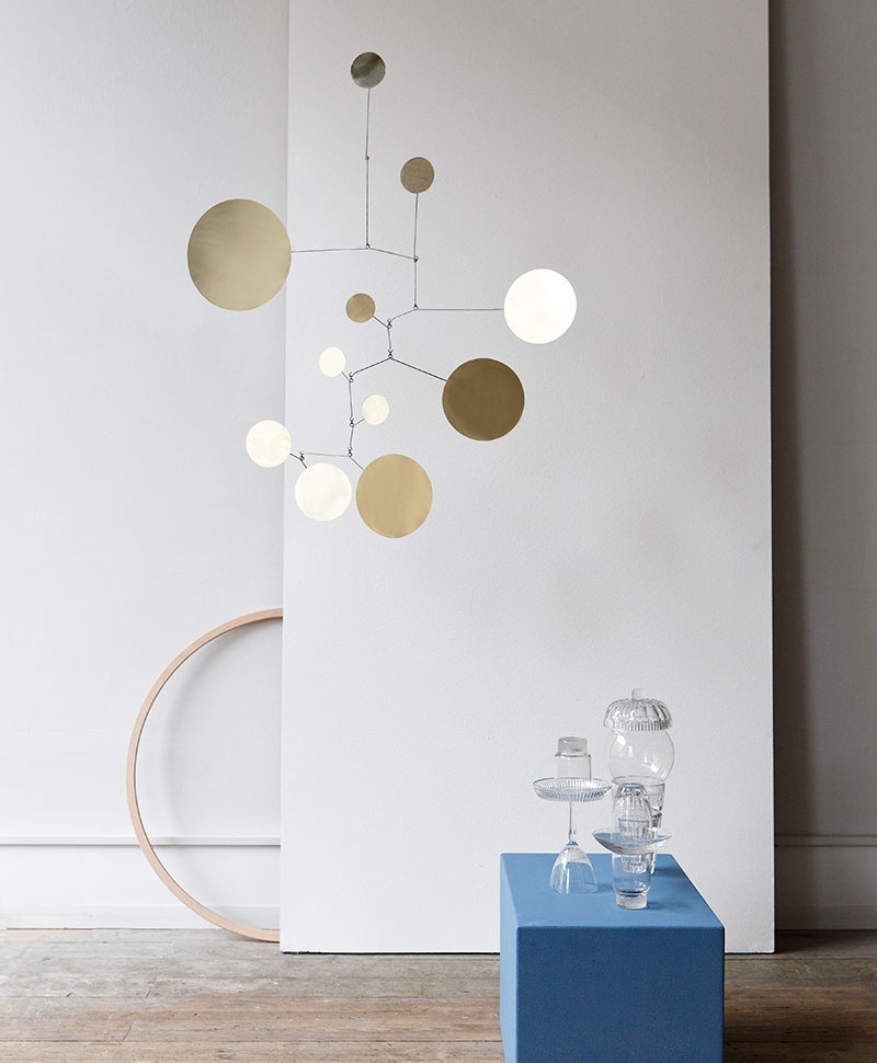 Das handgefertigte Mobile "Circle" hängt an der Decke vor einer grauen Wand in einem minimalistisch eingerichteten Raum