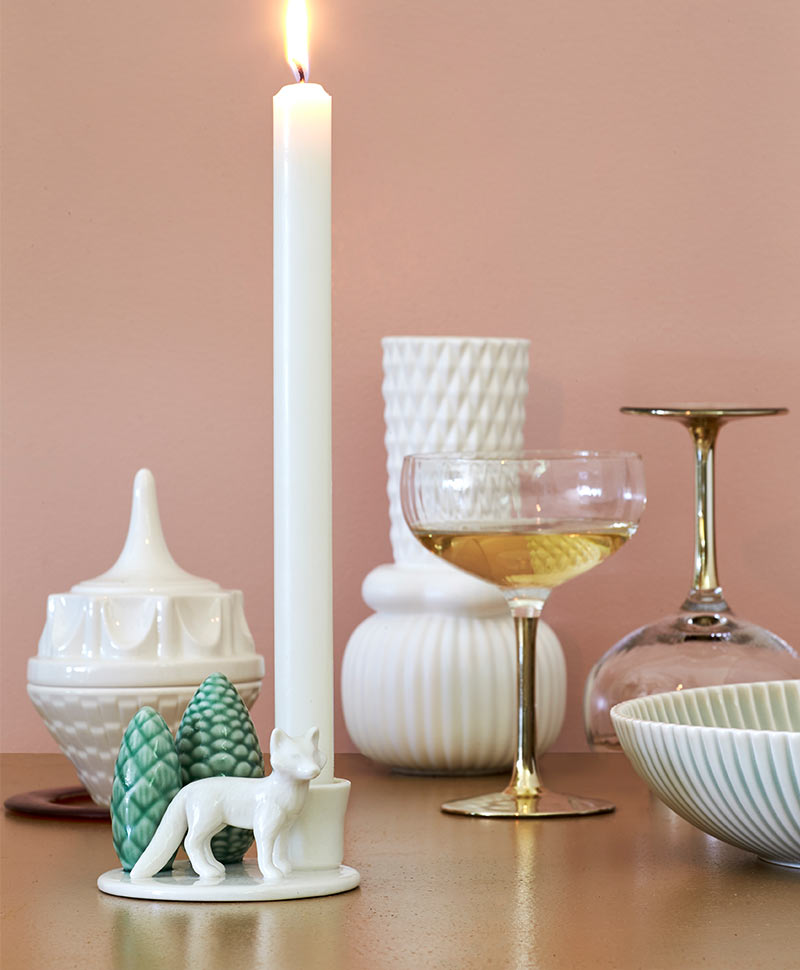 Ein Kerzenständer mit einem Fuchs und verschiedene Porzellangefäße neben einem Weinglas