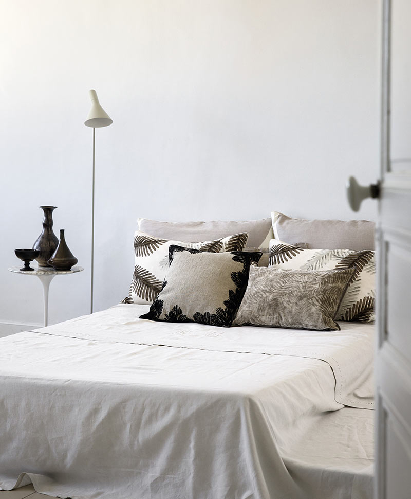 Élitiskissen in Nude- und Schwarztönen sind dekorativ auf einem Bett arrangiert