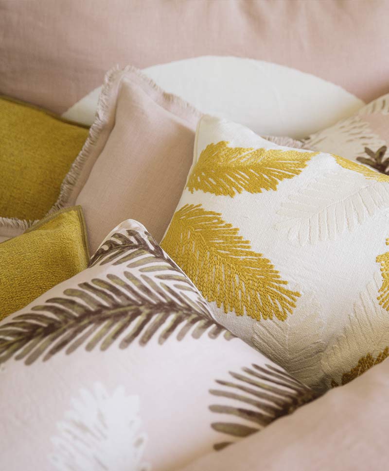 Élitiskissen in frischen Gelb- und Rosatönen sind dekorativ auf einem Bett arrangiert