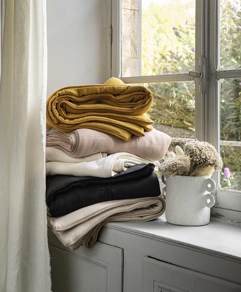 Decken in unterschiedlichen Farben auf einem Stapel auf einem Fensterbrett