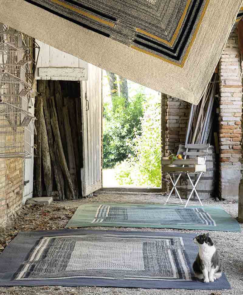 Zwei große Teppiche im Freien neben einer Katze