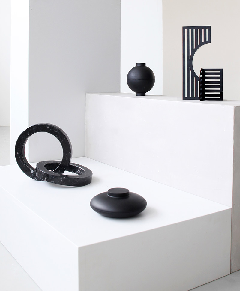 Moodfoto der Holzschatulle Wooden Sphere in der Farbe black, zusammen mit anderen Deko-Objekten der Marke Kristina Dam, die alle auf einer weißen Oberfläche arrangiert sind