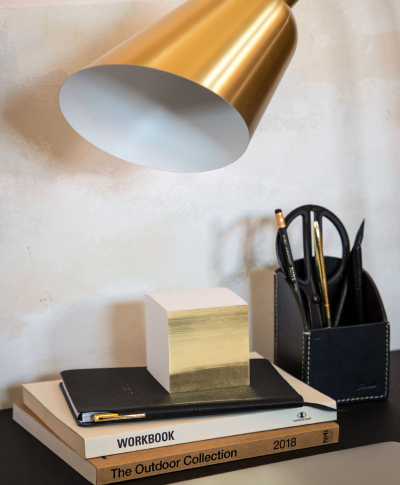 Ein Stapel Notizzetteln von GMUND Papier auf einem Schreibtisch unter einer Lampe