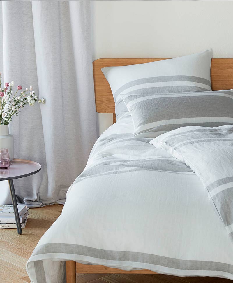 Eine weiß-grau gestreifte Bettwäsche auf einem Bett