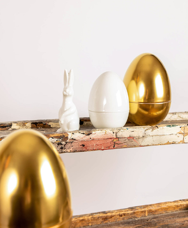 Ein Porzellanhase von Fürstenberg auf einem Regal mit zwei goldenen Eiern und einem weißen Ei