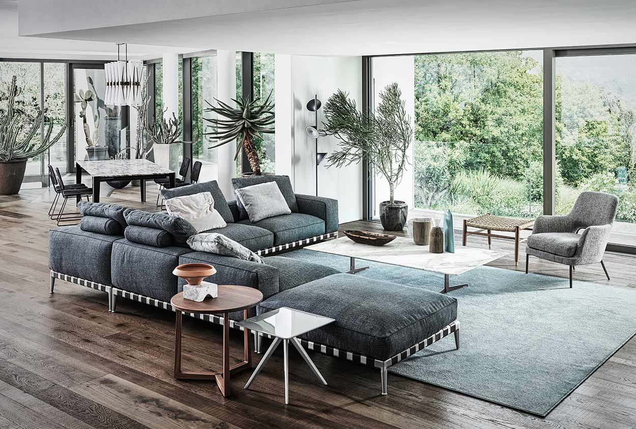 Ein großes Sofa von Flexform in einem Wohnraum kombiniert mit einem Sessel und verschiedenen Tischen