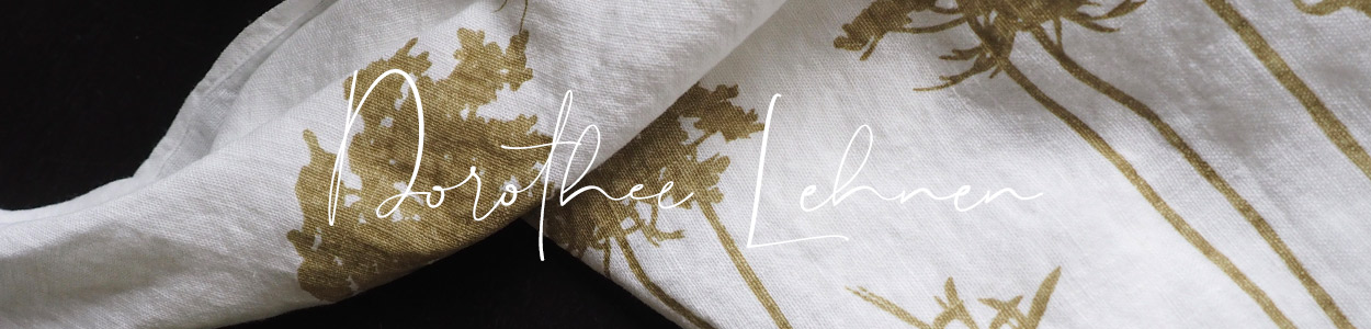 Markenbanner von Dorothee Lehnen mit einem weißen Leinen-Geschirrtuch mit goldenem Muster