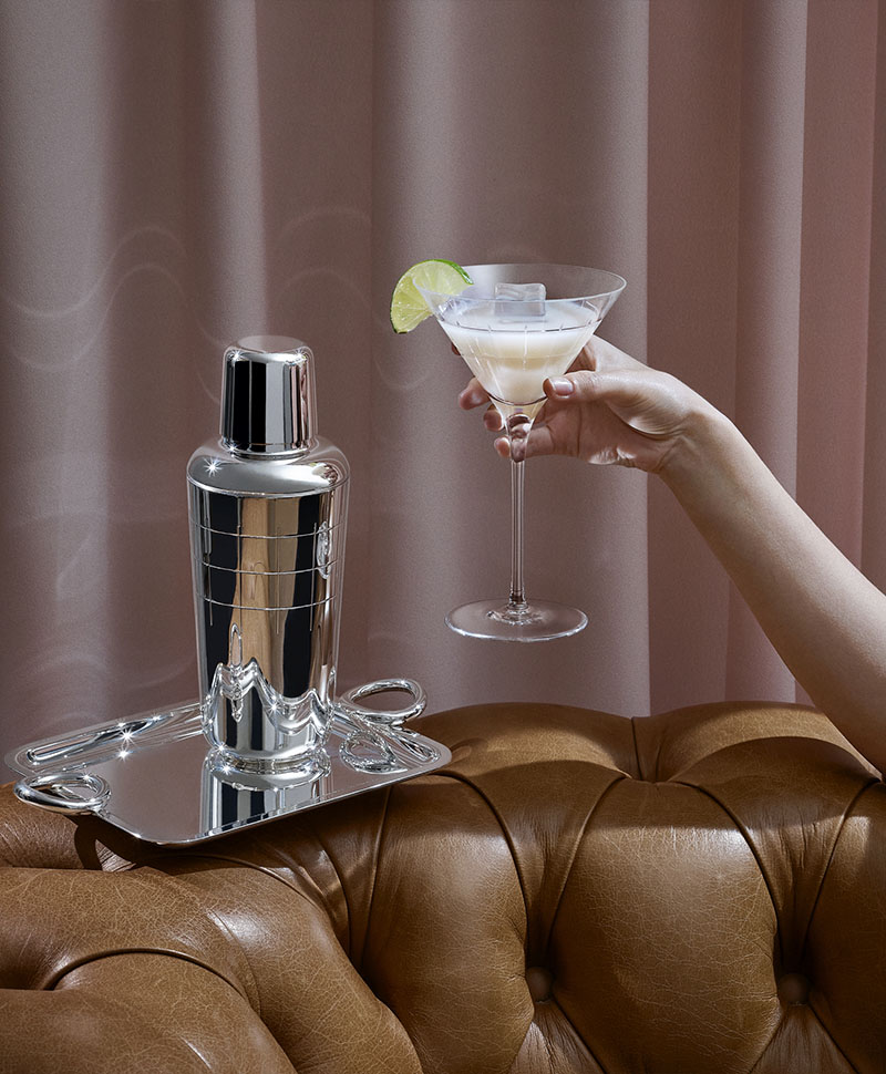 Ein Cocktail-Shaker auf einem Christofle Silbertablett auf der Lehne eines braunen Ledersofas